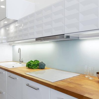 Elegant kitchen with white furniture, wooden countertop and floor and led lights on